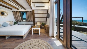 Une chambre avec un lit, une petite table et un téléviseur. Il y a une fenêtre avec des rideaux et une vue sur la plage.