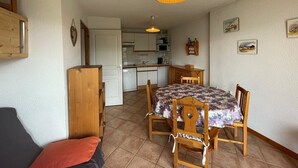 Ett kompakt bostadsutrymme med en matplats, ett kök och en liten sittgrupp.