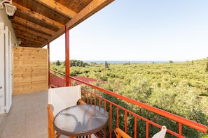 A balcony with a wooden ceiling, a glass table, and a red railing. - Mysa Nature Apartments (Zakynthos)