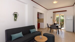 A modern living room with a sofa, a small round table, and a dining area with chairs and a table. - Mysa Nature Apartments (Zakynthos)