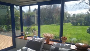 Une chambre dotée d’une grande fenêtre, d’un lit avec une literie à motifs et donnant sur un jardin.