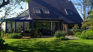 Une maison avec un toit en pente, de grandes fenêtres et un patio couvert.