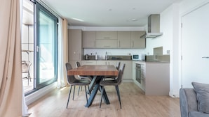 Une cuisine moderne avec une table à manger, des chaises et une porte-fenêtre coulissante donnant sur un balcon.
