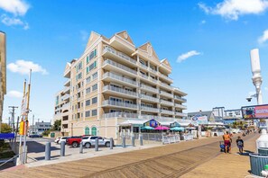 A multi-story hotel with balconies, a boardwalk, and beachside shops. - South Beach Boardwalk Condo (Ocean City)