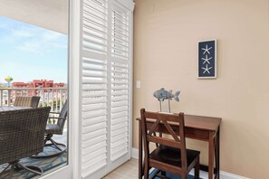 A balcony with a wicker chair and table, white shutters, and a wall-mounted star decoration.