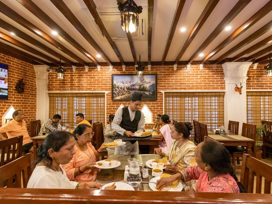 Un restaurante con paredes de ladrillo, vigas de madera y un cuadro grande de montañas.