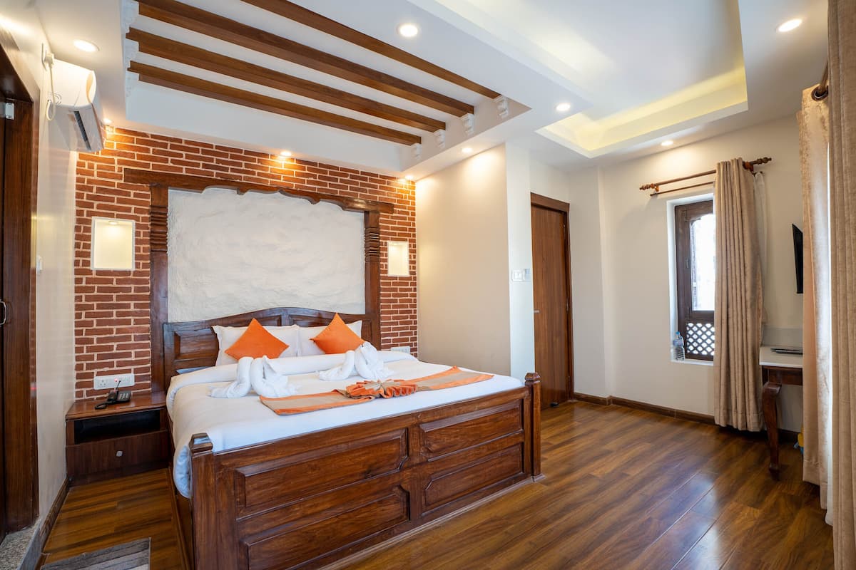 A bedroom with a wooden bed, brick wall, and a window with curtains.