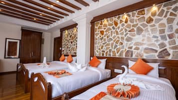 Ein Hotelzimmer mit zwei Betten, Holz-Kopfteilen, Wandverkleidung aus Stein und Holzboden.