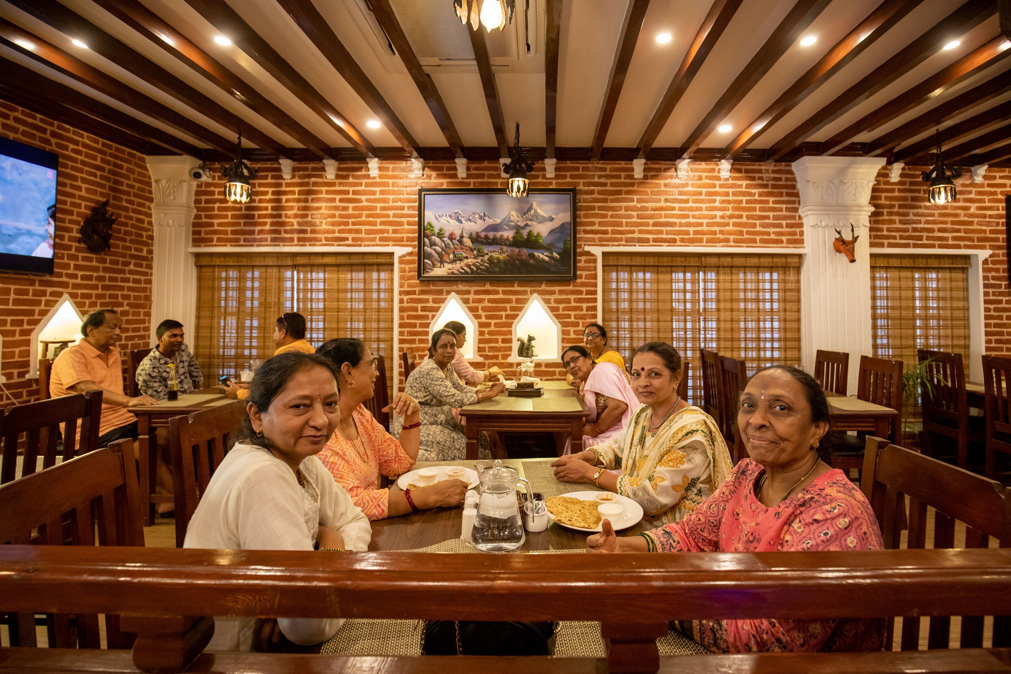 Restaurant amb parets de maó, bigues de fusta i un gran quadre d'un paisatge de muntanya.