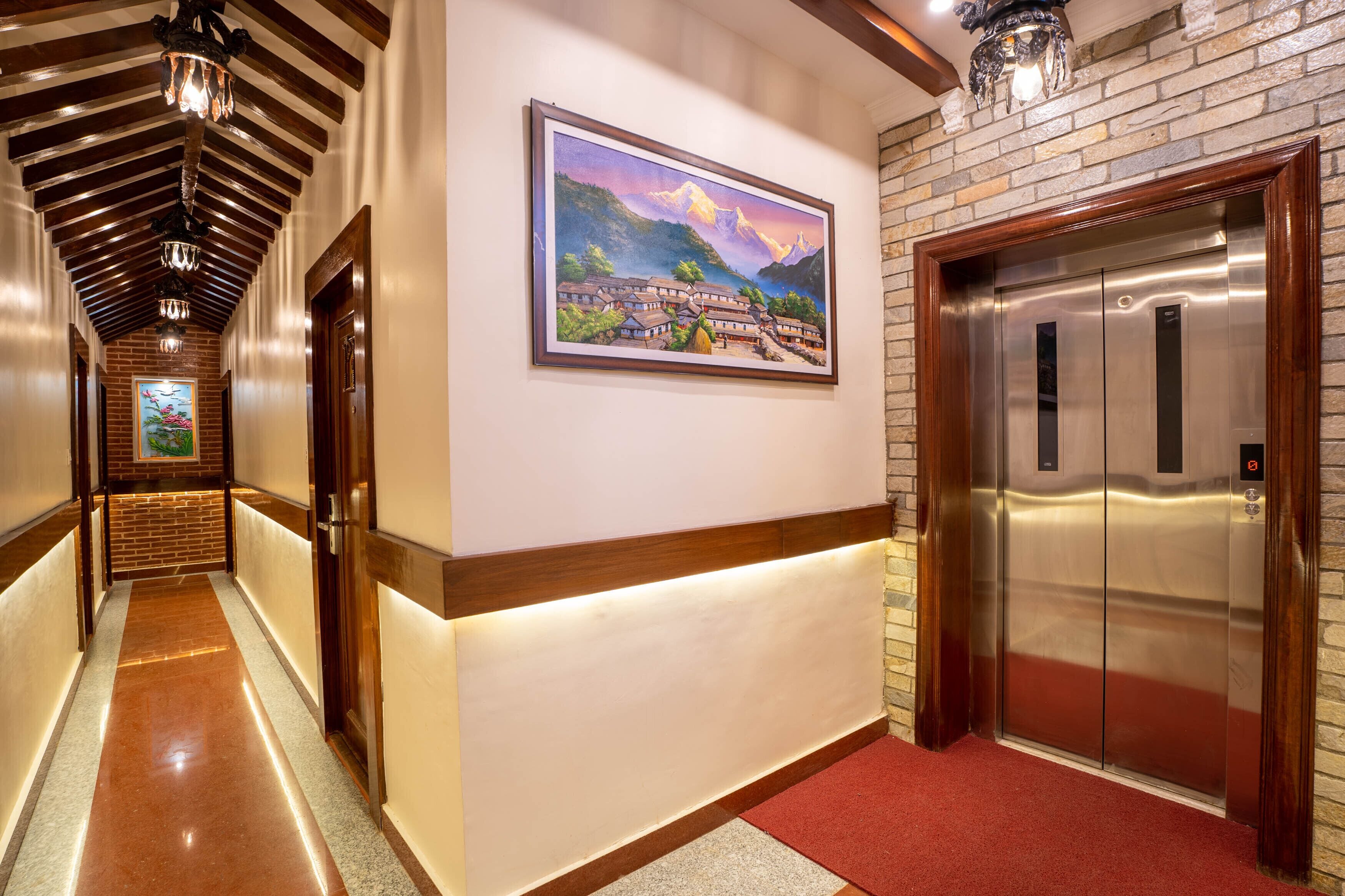 A hallway with a wooden ceiling, a framed painting, and an elevator.