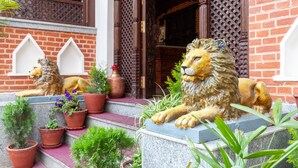A building entrance with a lion statue, brick walls, and potted plants. - Airport Himalaya Boutique Hotel (Kathmandu)