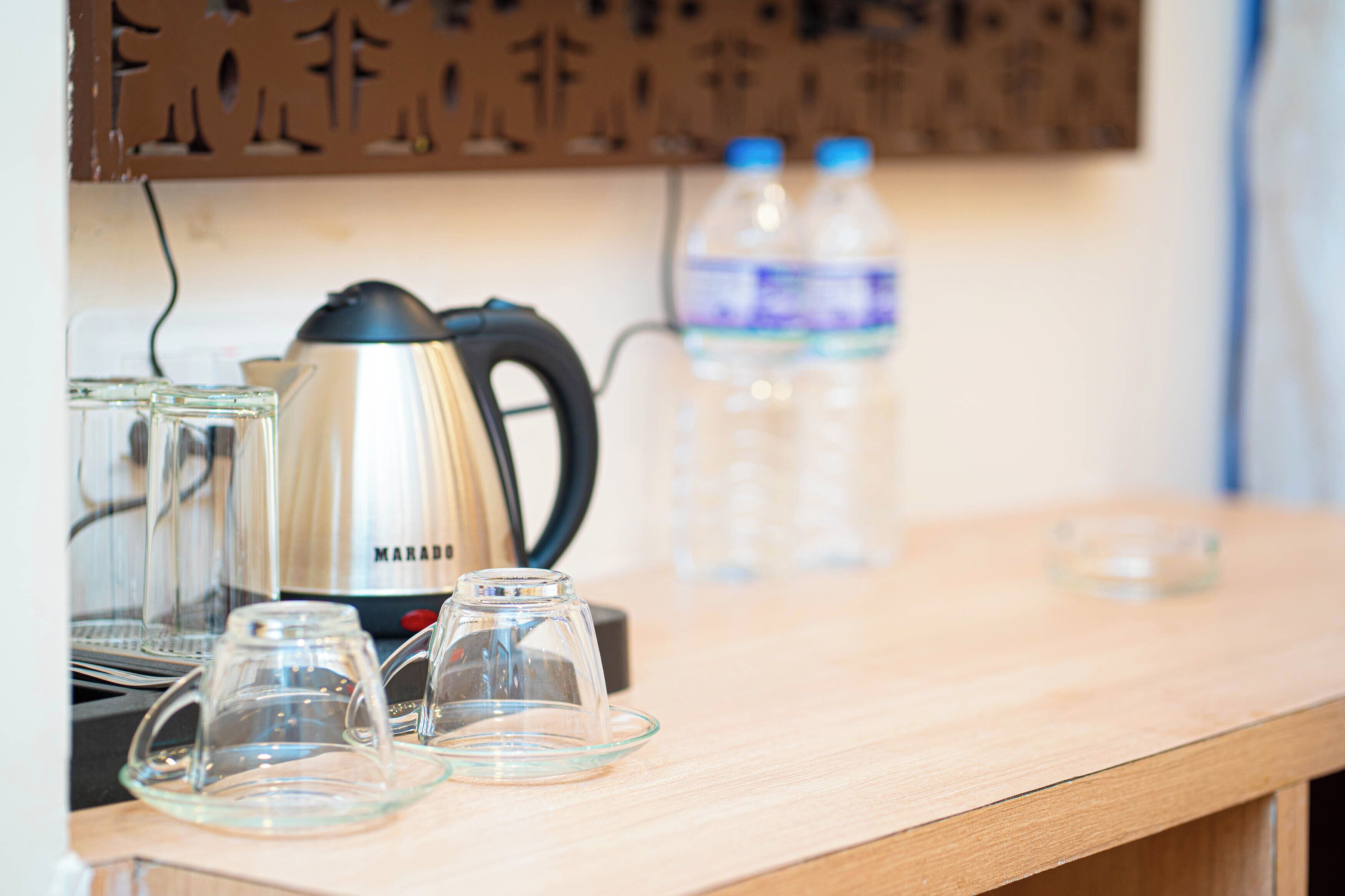 A kitchen counter with a coffee maker, two water bottles, and three glass cups.