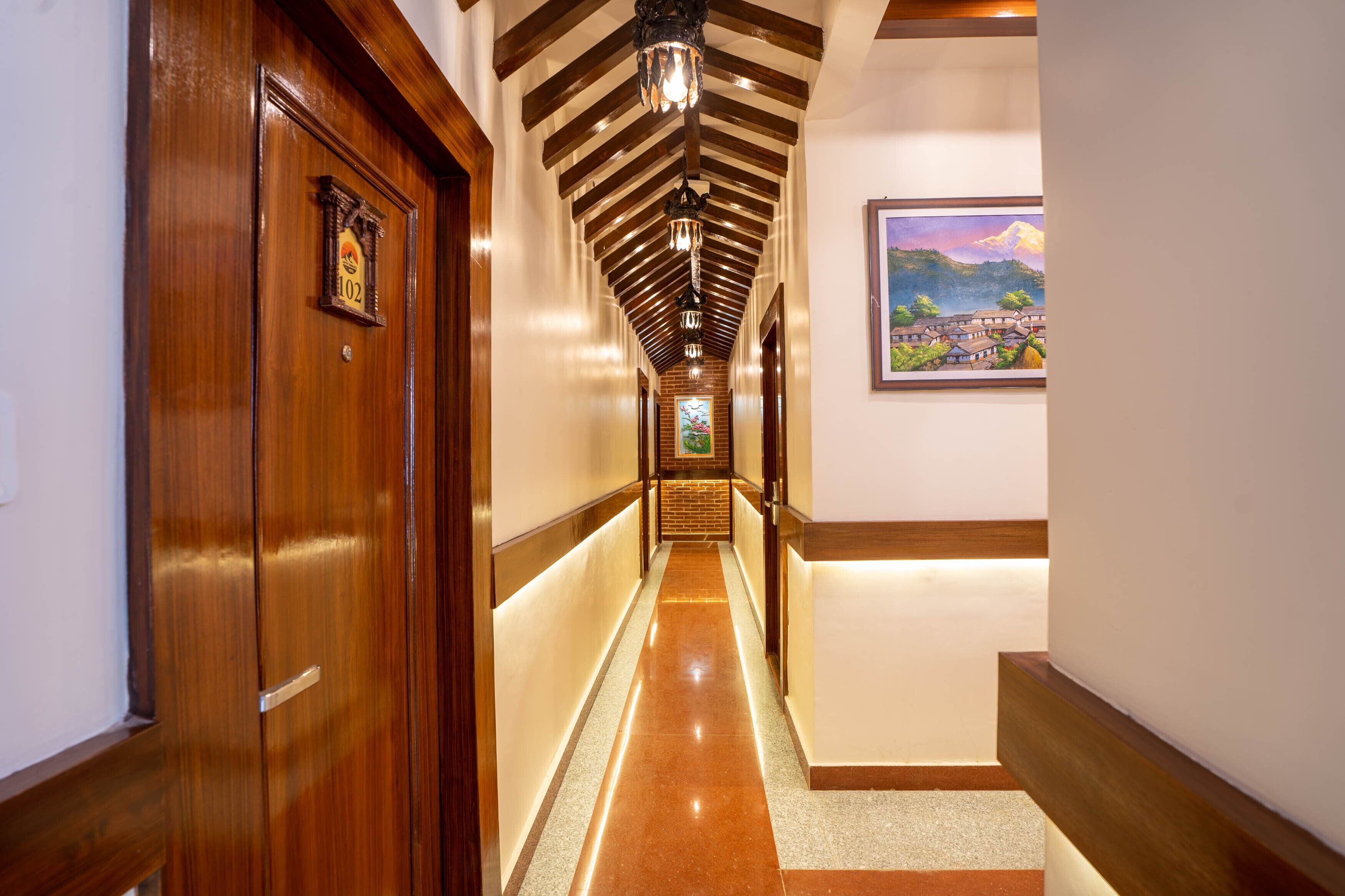 A hallway with wooden doors, a tiled floor, and a wooden ceiling with exposed beams.