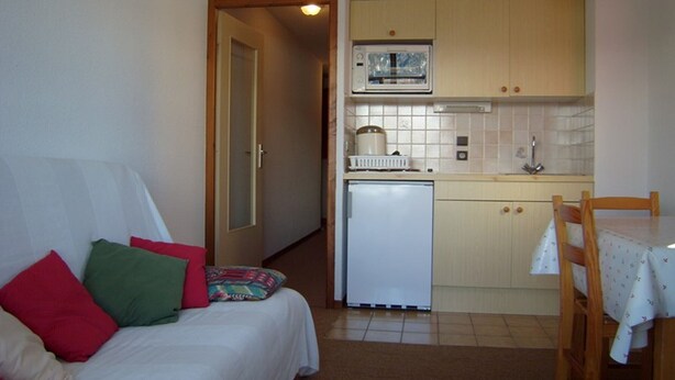 Ein kleines Zimmer mit Bett, einer Küchenzeile und einem Essbereich.