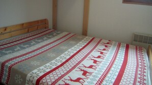 Ein Einzelbett mit einem gemusterten Überwurf, einem Holzkopfende und einem Fenster mit Holzrahmen.