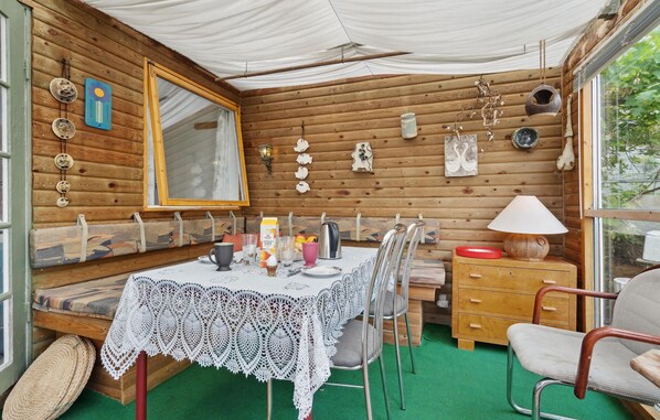 A cozy wooden cabin with a dining table set for two, a bench, and a small cabinet. - Lovely home in Hejls with WiFi (Hejls)