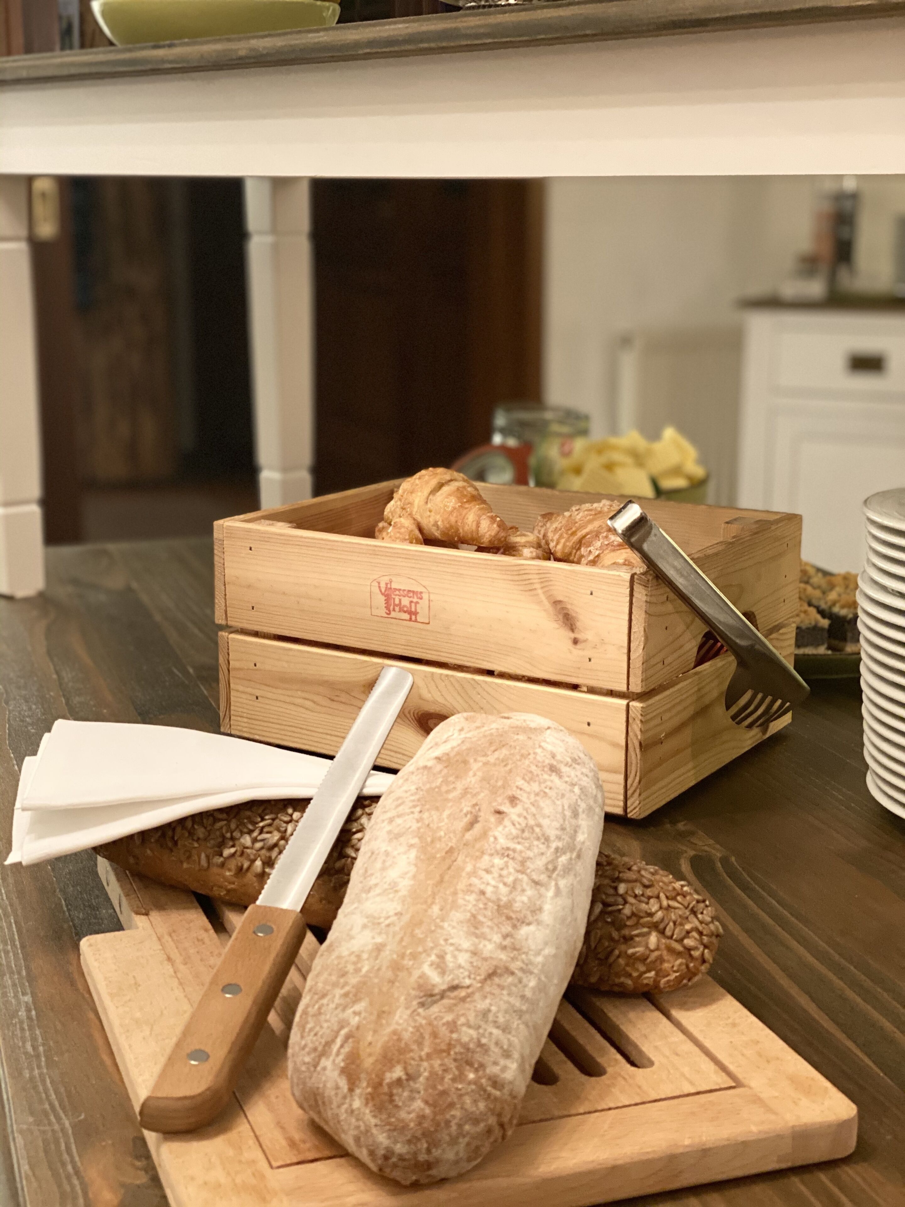 Una caja de madera para pan con un cuchillo y una hogaza sobre una tabla de cortar.