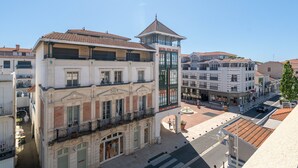 A historic building with a central tower, a covered walkway, and a street with shops and pedestrians. - "Charming Studio in Central Arcachon with Balcony, Steps from Beach - Sleeps 2" (Arcachon)