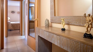 A hotel room with a wooden door leading to a bathroom, a large mirror, and a statue on the dresser. - Seaside Apartment with Parking and AC (Torredembarra)