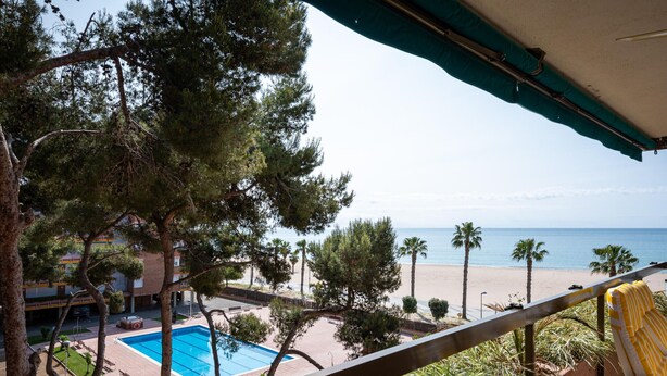 A balcony with a view of a swimming pool, beach, and ocean. - Seaside Apartment with Parking and AC (Torredembarra)