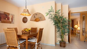 A dining area with a table set for four, surrounded by wicker chairs. There is a potted bamboo plant to the right. - Seaside Apartment with Parking and AC (Torredembarra)