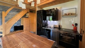 A modern kitchen with wooden beams, a dining table, and stainless steel appliances. - Cozy duplex apartment 4 pers, parking (Crest-Voland)
