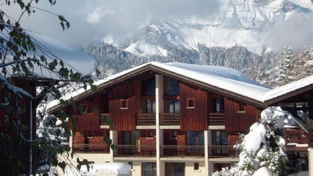 A chalet-style building with a sloped roof, multiple balconies, and a view of snow-covered mountains. - Cozy duplex apartment 4 pers, parking (Crest-Voland)