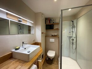 Um banheiro moderno com pia, vaso sanitário e chuveiro com divisória de vidro.