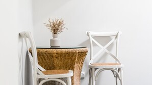 Un coin avec une chaise blanche, une table en osier ornée d’un vase de fleurs séchées et un mur blanc.