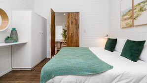 Une chambre à coucher avec un lit, une armoire en bois, un bureau et une vue sur la plage par la fenêtre.