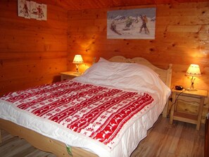 Une chambre rustique en bois avec un lit, deux tables de chevet avec des lampes et un tableau au mur.