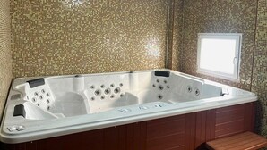 Un jacuzzi con banco de madera, ventana y paredes de mosaico.
