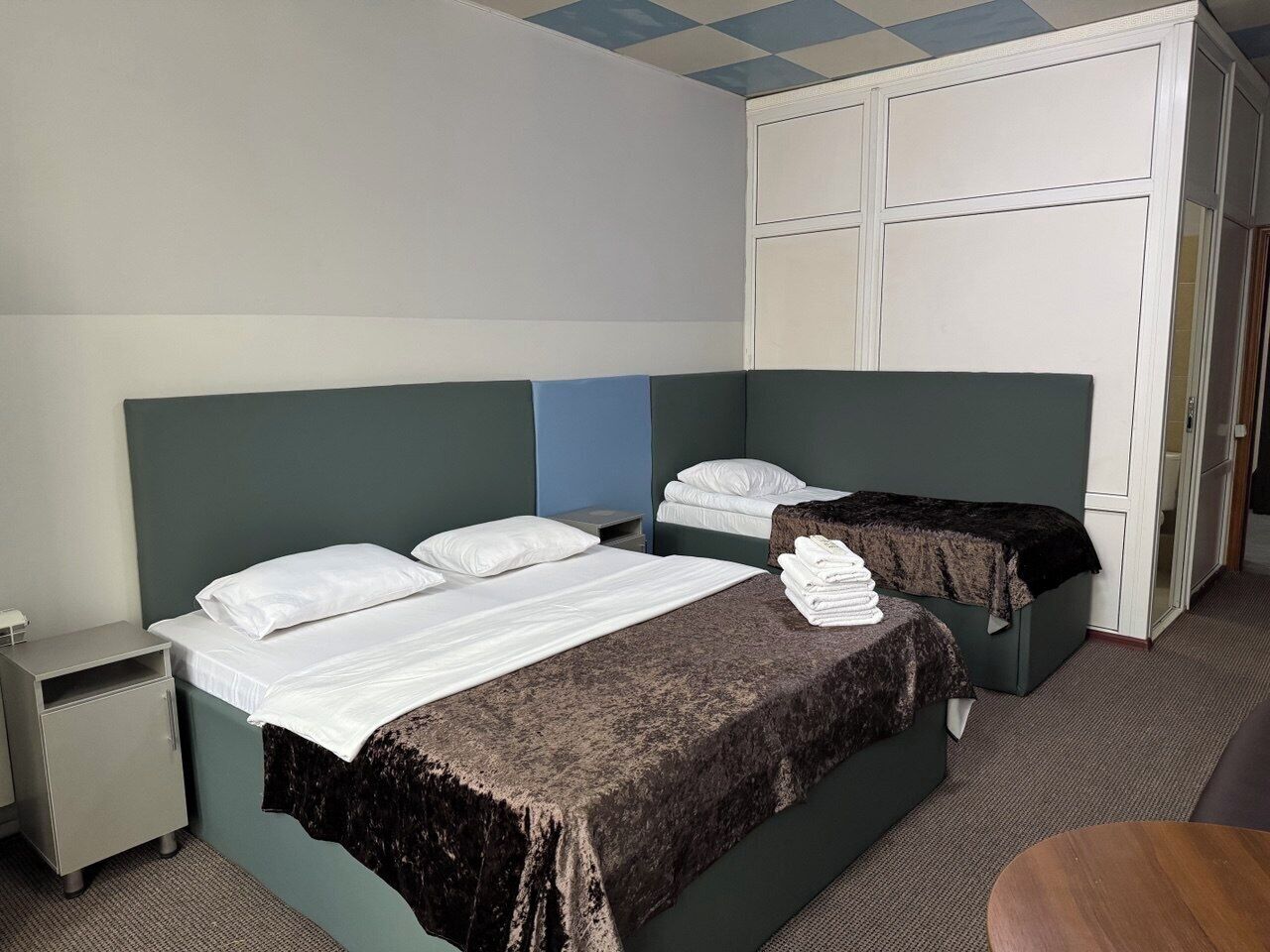 Habitación de hotel con dos camas, un armario, un escritorio y una mesita.