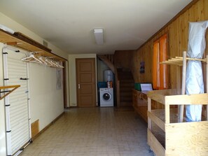 Una sala de lavandería con lavadora, tendedero y banco de madera.