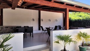 An outdoor patio with wooden beams, tables, chairs, and potted plants. - Castello Gulich (Porec)