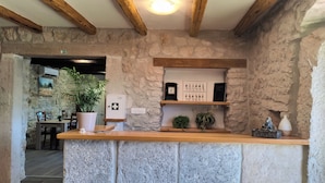 A stone reception desk with a wooden counter, a potted plant, and a wall-mounted emergency light. - Castello Gulich (Porec)