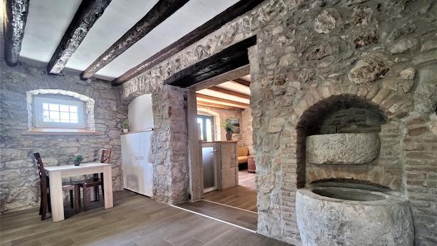 A rustic kitchen with stone walls, a wooden table, and a built-in oven. - Castello Gulich (Porec)