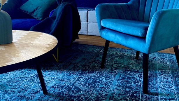 A modern living room with a blue sofa, a blue armchair, a round coffee table, and a patterned rug. - Schängel Chic apartment centrally located in the old town (Koblenz)