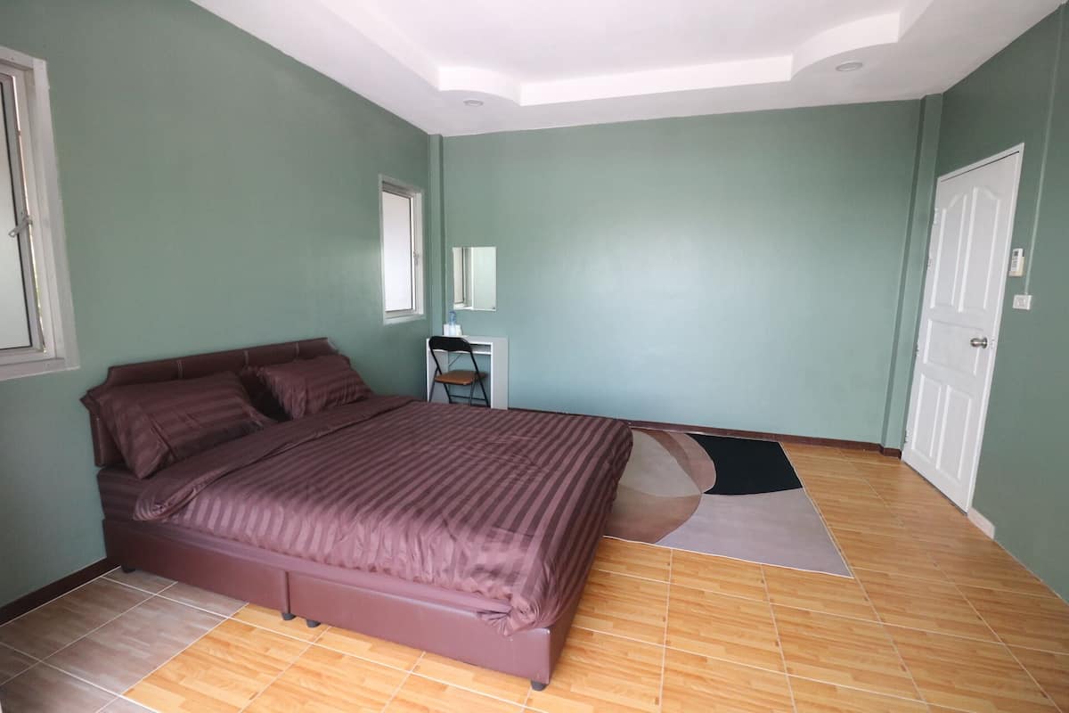 Un dormitorio con cama, escritorio, silla, espejo y puerta.