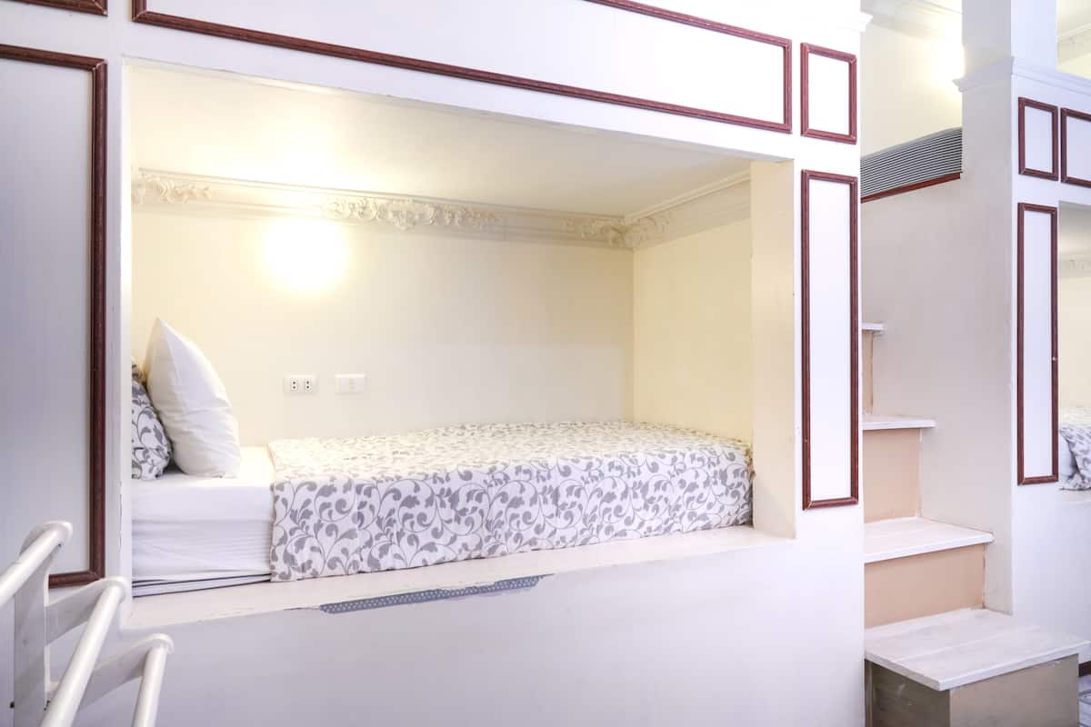 Una habitación con literas, una ventana pequeña y una escalera.
