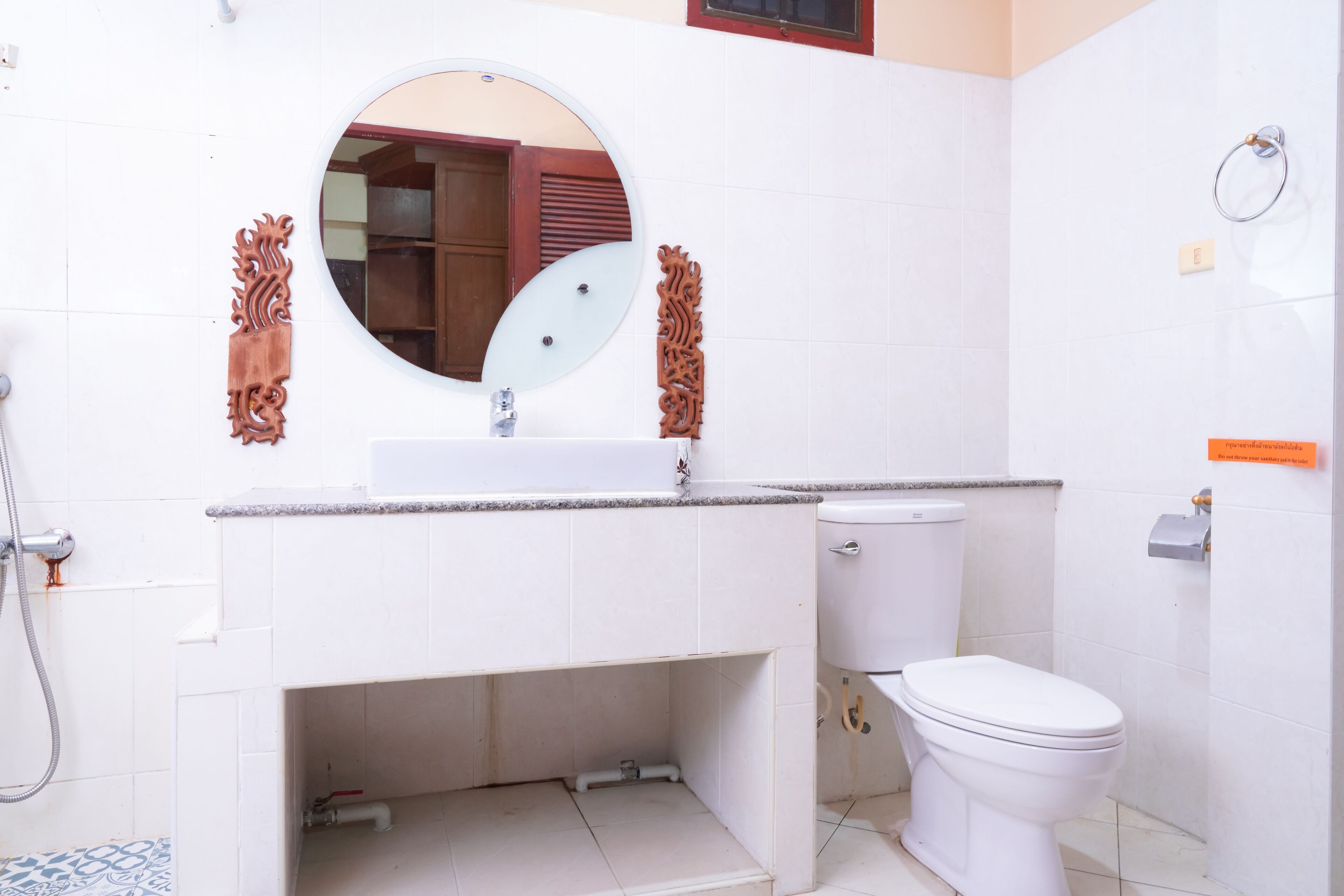 Un baño con un lavabo blanco, un inodoro y un espejo redondo.