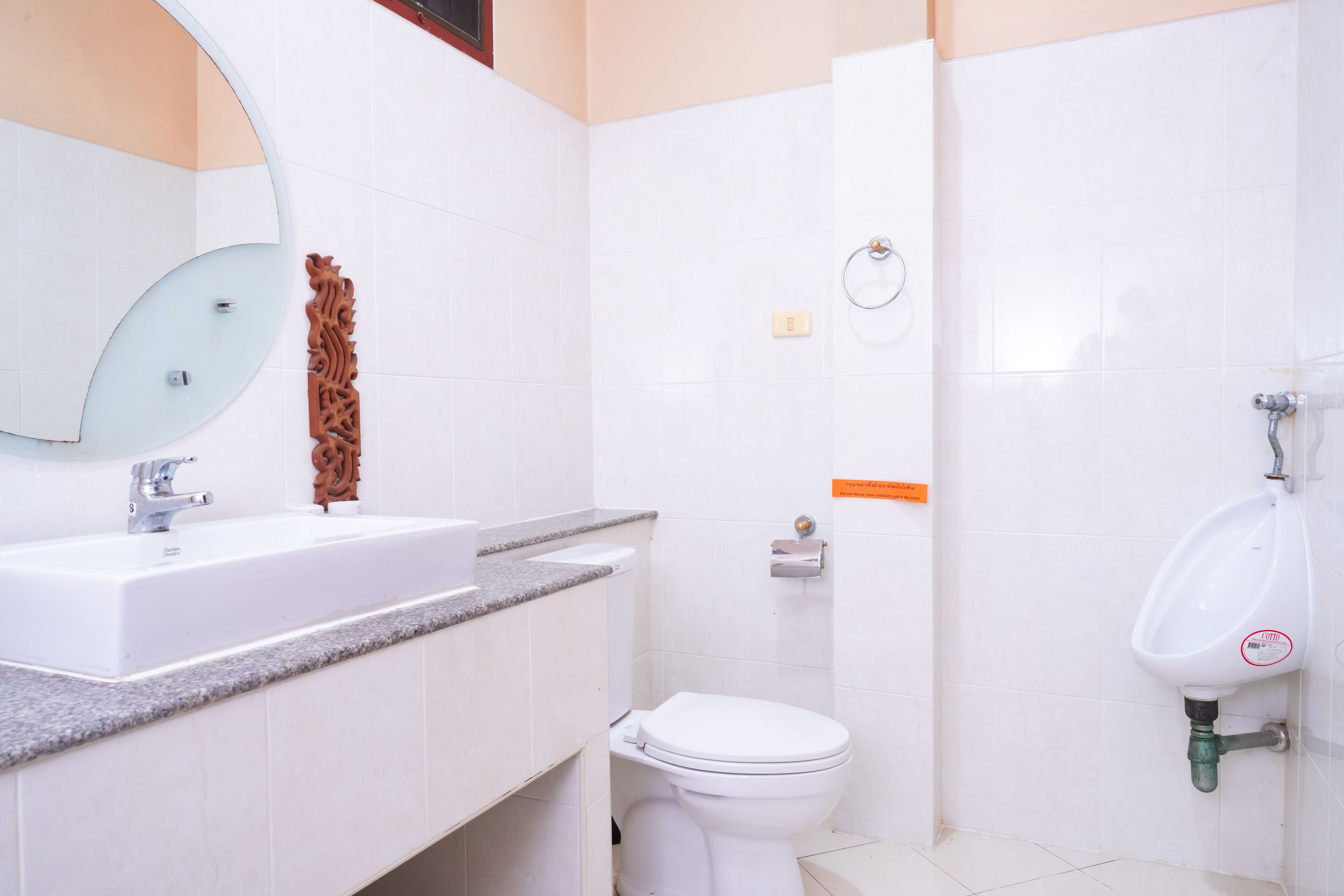 Un baño con lavamanos, espejo, inodoro y orinal.
