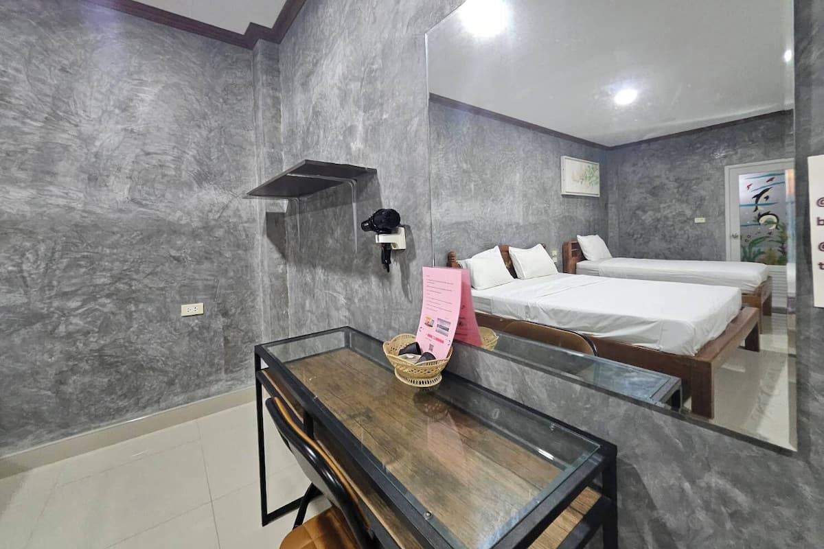 Habitación de hotel moderna con un espejo grande, dos camas individuales, una mesita con una cesta y un estante empotrado.