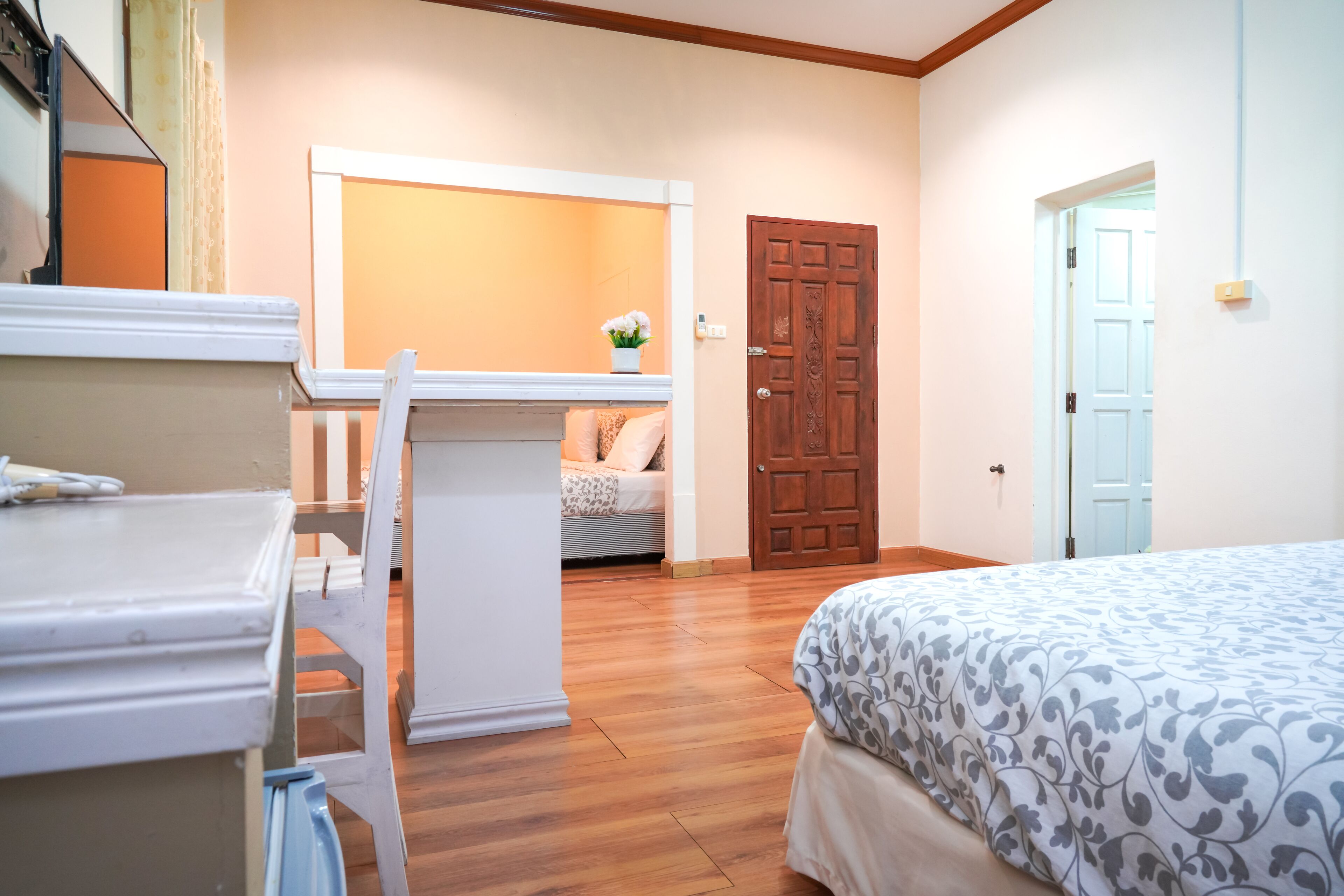 A bedroom with a bed, a desk, and a chair. There is a door and a window in the room.