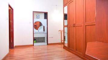 Una habitación con suelo de madera, un armario de madera y un espejo.