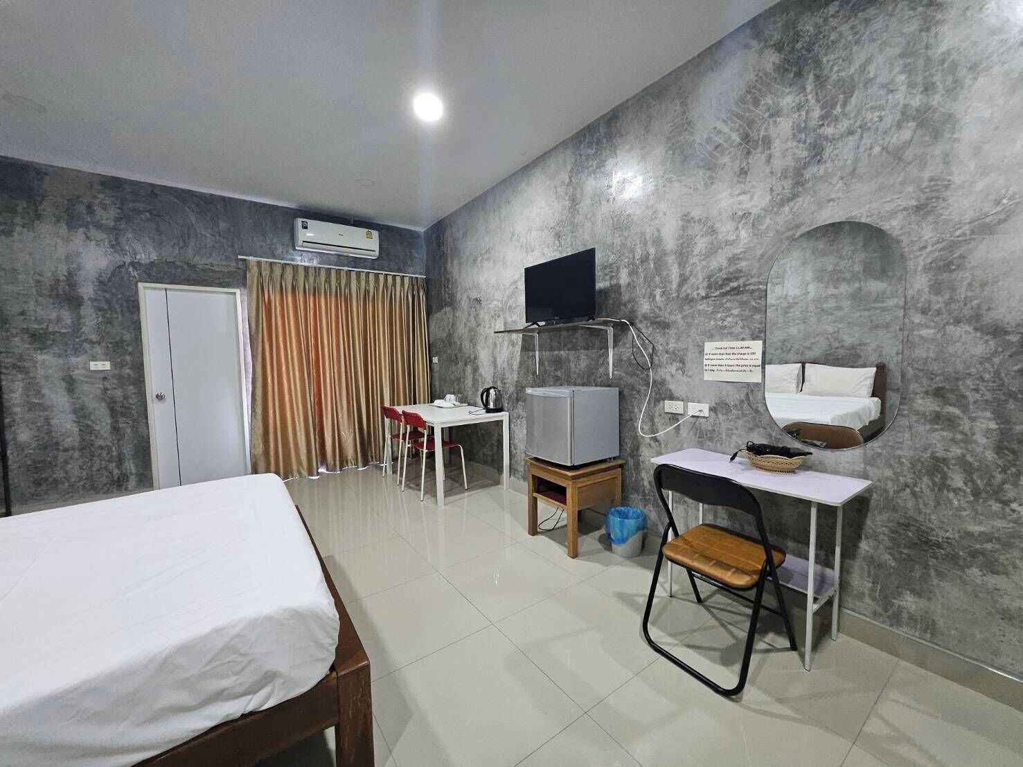 A hotel room with a bed, a desk with a chair, a television, and a mirror.