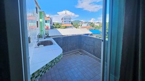 A balcony with a view of colorful buildings and a clear sky. - Guesthouse Phuket Airport (Sa Khu)