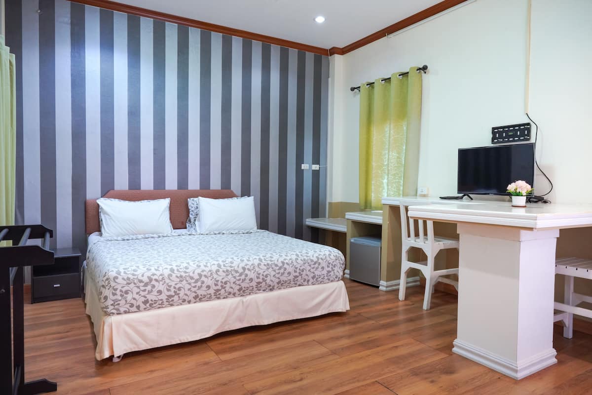 Un dormitorio ordenado con cama, escritorio y silla.