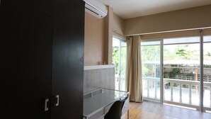 A room with a sliding glass door leading to a balcony, a ceiling-mounted air conditioner, and a dark-colored wardrobe. - Guesthouse Phuket Airport (Sa Khu)