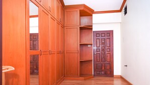 A corner room with wooden cabinets, a wooden door, and a white wall. - Guesthouse Phuket Airport (Sa Khu)